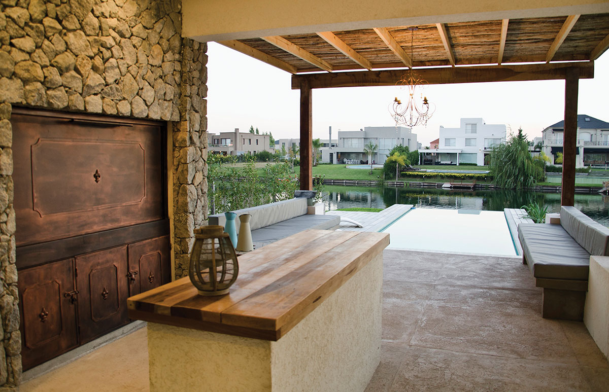 La parrilla con su barra-bar, se ubica antes del estar con bancos de mampostería y almohadones. Luego, la piscina con borde infinito y el lago. Como para quedarnos allí a vivir... (Housing Construcciones) 